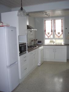 een keuken met witte kasten en een witte koelkast bij Meublé de tourisme Le Gilliard in Chavanges