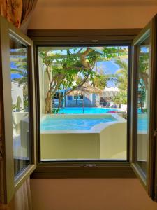 a window with a view of a swimming pool at Zephyros Hotel in Kamari
