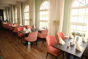 a dining room with tables and chairs and windows at Seepavillon Rheinsberg in Rheinsberg