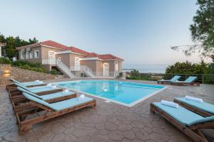a swimming pool with lounge chairs and a house at Iliovasilema in Platy