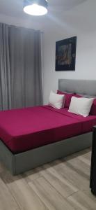 a large bed with pink sheets and white pillows at Apartmentos Timas #1 in Praia