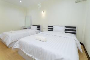 two beds in a room with white sheets at Thai Guest House in Ban Don Klang