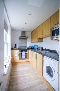 a kitchen with wooden cabinets and a washer and dryer at The Oystercatcher At The Bay, Filey in Filey