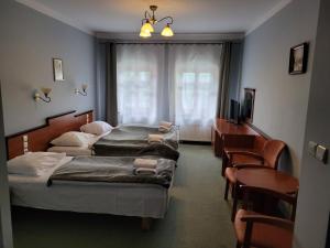 a hotel room with two beds and a tv at Hotel Leliwa in Leśna