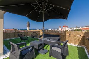 une terrasse avec une table, des chaises et un parasol dans l'établissement Renaissance Apartment, feeling the heartbeat of Rethymno!, à Réthymnon