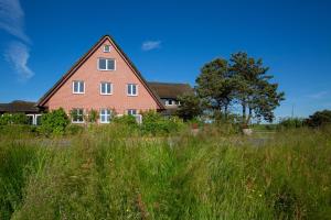 een groot stenen huis in een veld van hoog gras bij Hotel MeerLand Pellworm in Pellworm