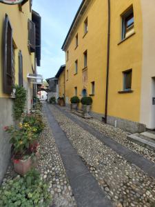an empty street between two buildings with potted plants at B&B Romantico Palazzo dei Ulivi in Purasca