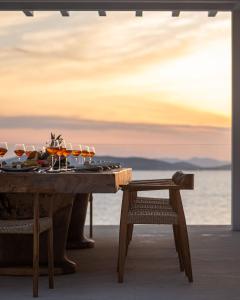 a wooden table with wine glasses and a stool at Villa Santa Esmeralda Mykonos in Agios Ioannis Mykonos