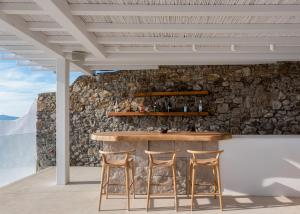 a bar with two stools and a stone wall at Villa Santa Esmeralda Mykonos in Agios Ioannis Mykonos