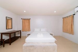 a bedroom with a white bed and a table at Surfer's Village in Khao Lak