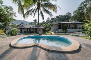 a house with a swimming pool in the middle of a driveway at Surfer's Village in Khao Lak