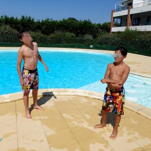 two young boys standing next to a swimming pool with a mask at Petite maison dans résidence avec piscine proche plage et centre ville à pied in Pornic