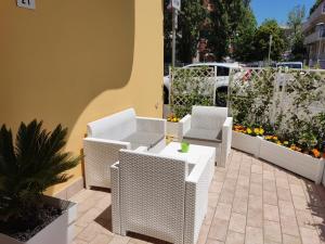 eine Terrasse mit weißen Korbstühlen und einem Tisch in der Unterkunft Residence Yellow in Rimini