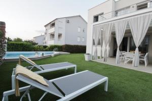 un patio con sillas, una piscina y un edificio en Villa Pura Vida with pool, en Savudrija