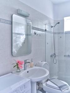 biała łazienka z umywalką i lustrem w obiekcie Ifestos home with private veranda, Paros w mieście Logaras