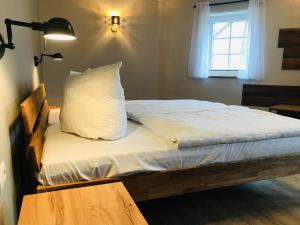 ein Bett mit einem Kissen, einer Lampe und einem Fenster in der Unterkunft Landkulturhof Glücksbringer in Rudolstadt