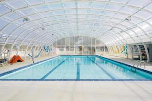 a large indoor swimming pool with a glass ceiling at Camping Nature L'Airial in Soustons