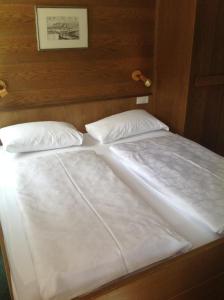 1 cama con 2 sábanas y almohadas blancas en Garni Pineta, en San Martino in Badia