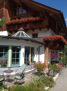 une maison avec des chaises et des fleurs devant elle dans l'établissement Garni Pineta, à San Martino in Badia