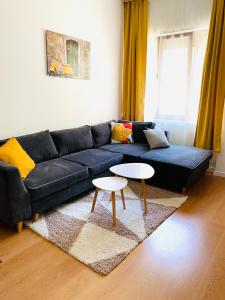 sala de estar con sofá negro y 2 mesas en Уютен апартамент в сърцето на прекрасен град Варна en Varna