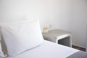 a bed with white sheets and a side table at Aetheria Villas in Oia