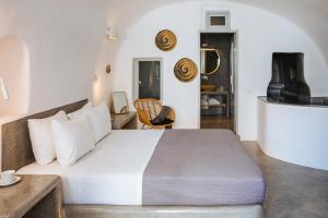 a bedroom with a large white bed and a chair at Aetheria Villas in Oia