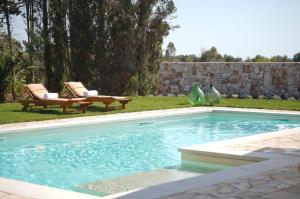 a swimming pool in a yard with two chairs at Agriturismo Tenuta Carrino in Porto Cesareo