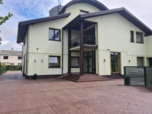 a white house with a black roof at Medziotoju kiemelis in Palanga