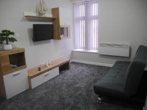 a living room with a couch and a tv and a chair at Mermaid Holiday Flats in Blackpool