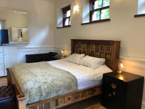 a bedroom with a bed with a wooden frame and windows at The Coach House in Skelmorlie