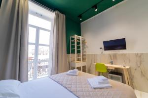 Schlafzimmer mit einem Bett, einem Schreibtisch und einem Fenster in der Unterkunft P.C. Boutique H. De Gasperi, Napoli Centro, by ClaPa Group in Neapel