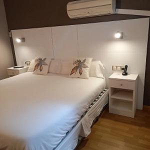 1 dormitorio con 1 cama blanca grande y mesita de noche en Hotel El Acebo, en Jaca