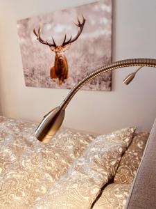 una lámpara en una cama con un ciervo en la pared en The Lodge Braunlage en Braunlage
