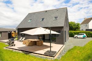 a house with a patio with an umbrella at Charmante maison pour 5 au coeur de Penmarch in Penmarch