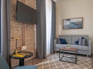 a living room with a couch and a tv on a brick wall at Home Art Apartments Málaga in Málaga