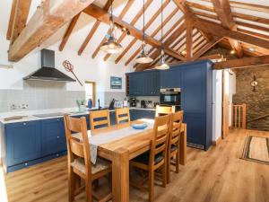 a kitchen with blue cabinets and a wooden table and chairs at Ty Gwennol in Beaumaris