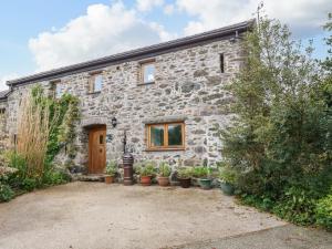 a stone house with potted plants in front of it at Ty Gwennol in Beaumaris