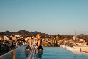 a woman in a hat sitting on the edge of a swimming pool at Hotel Boutique Can Pocovi in Sant Llorenç des Cardassar