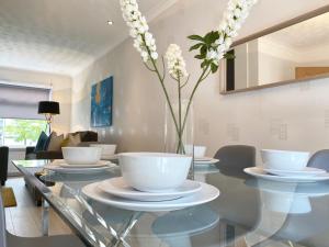 a dining room with a glass table with a vase of flowers at Telford View in East Kilbride