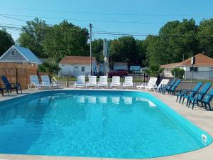 uma grande piscina azul com cadeiras e cadeiras em The Palms Motel em Geneva-on-the-Lake