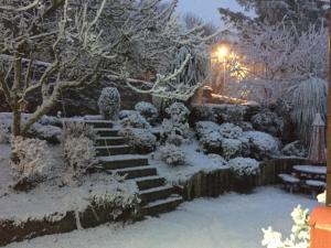 a garden covered in snow with stairs and trees at The Coach House in Skelmorlie