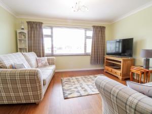 a living room with two couches and a flat screen tv at Rhos Deiniol in Porthmadog