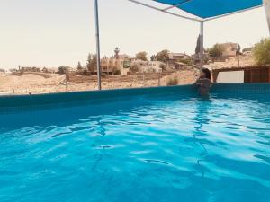 a woman standing in a pool of blue water at Tamar's House in Arad