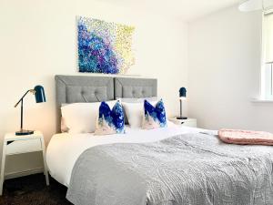 ein Schlafzimmer mit einem großen weißen Bett mit blauen Kissen in der Unterkunft Waverley in East Kilbride