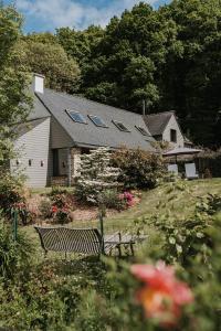 ein Haus mit einer Bank in einem Garten mit Blumen in der Unterkunft Gîtes du Bulz, en pleine forêt proche de la mer in Pleyber-Christ