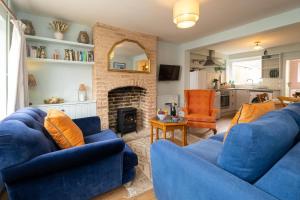 a living room with two blue couches and a fireplace at Quay Cottage - Aldeburgh Coastal Cottages in Aldeburgh