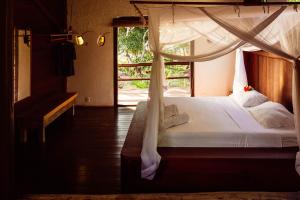 a bedroom with a white bed with a window at Casa Alto Mucuge in Arraial d'Ajuda