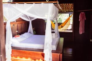 1 dormitorio con cama con dosel y hamaca en Casa Alto Mucuge, en Arraial d'Ajuda