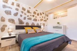 a bedroom with a bed and a stone wall at Elysium Olival en Casa La Fuentita in El Charco +15 photos
