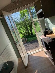 an open door leading to a yard with a view at Rhodes To Serenity - Waterfall Shepherds Hut in Cauldon